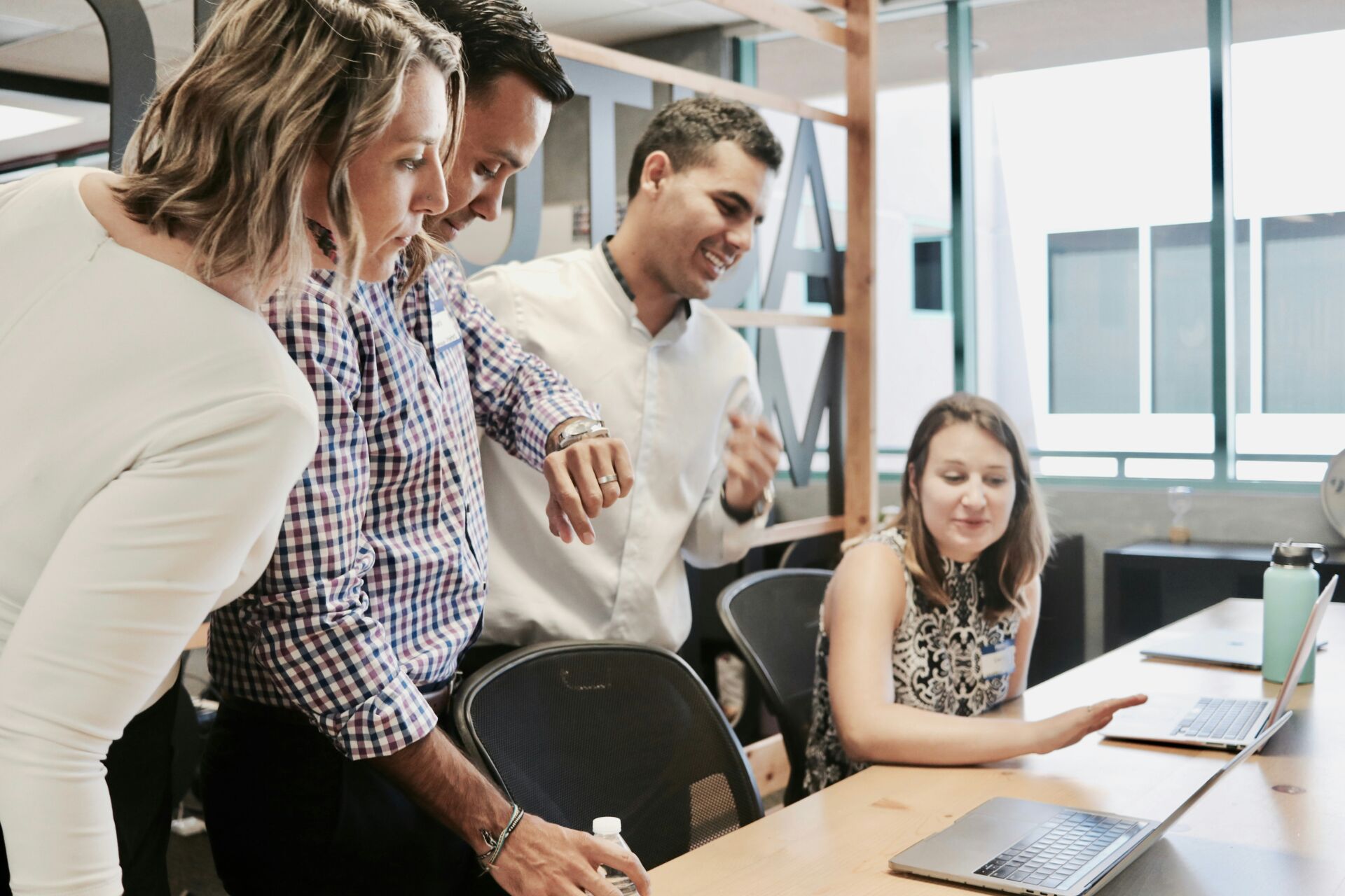 Vier Personen unterhalten sich angeregt um einen Laptop in einer Büroumgebung über das Management Trainee-Programm bei der HANSETRANS Holding GmbH in Hamburg.